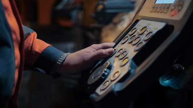 A close-up of the asphalt paver's control panel. Road worker's hand at the asphalt paver's console. Road repair, construction of a new road in the city. 