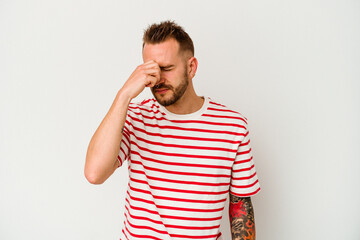 Young tattooed caucasian man isolated on white background having a head ache, touching front of the face.