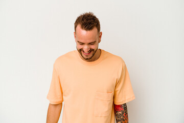 Fototapeta premium Young tattooed caucasian man isolated on white background laughs and closes eyes, feels relaxed and happy.