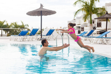 Naklejka premium Father playing with his daughter in swimming pool