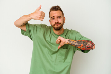 Young tattooed caucasian man isolated on white background showing thumbs up and thumbs down,...