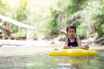 Little  girl sitting in inflatable tube against streams background.
