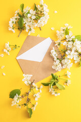 Blank white paper in envelope and flowers around it on paper color background