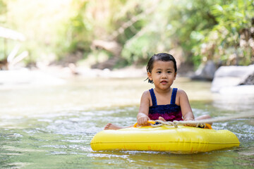 Little  girl sitting in inflatable tube against streams background.