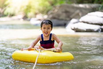 Little  girl sitting in inflatable tube against streams background.