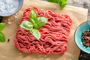 Minced meat with spices on paper on table. Closeup