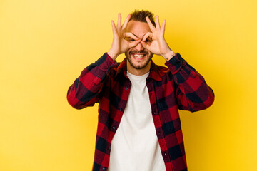 Young tattooed caucasian man isolated on yellow background excited keeping ok gesture on eye.