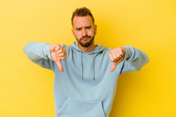 Fototapeta premium Young tattooed caucasian man isolated on yellow background showing a dislike gesture, thumbs down. Disagreement concept.