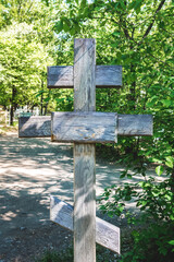 An old wooden cross stands on an abandoned grave in the city cemetery.