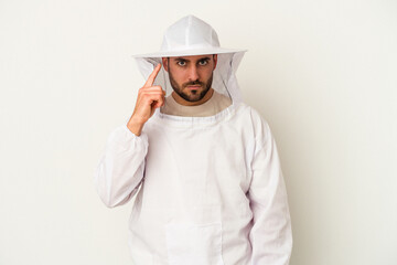 Young apiculture caucasian man isolated on white background pointing temple with finger, thinking, focused on a task.