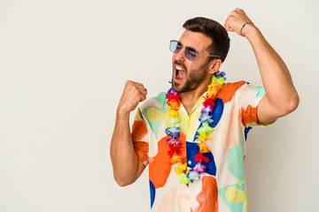 Young caucasian man dancing on a hawaiian party isolated on white background raising fist after a...