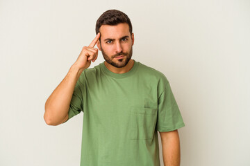 Young caucasian man isolated on white background pointing temple with finger, thinking, focused on a task.