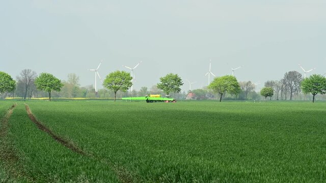 Traktor mit Feldspritze beim Ausbringen von Pflanzenschutzmittel gegen Pestizid