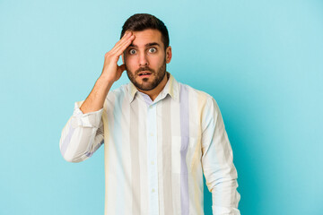 Young caucasian man isolated on blue background being shocked, she has remembered important meeting.