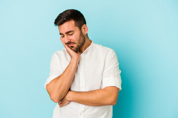 Young caucasian man isolated on blue background who is bored, fatigued and need a relax day.