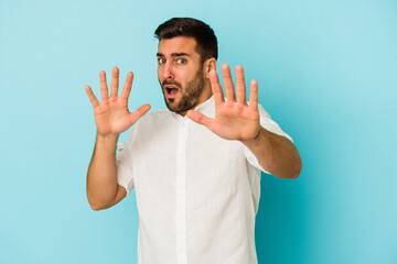 Young caucasian man isolated on blue background being shocked due to an imminent danger