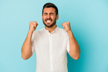 Fototapeta premium Young caucasian man isolated on blue background celebrating a victory, passion and enthusiasm, happy expression.