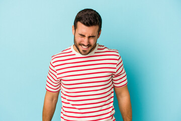 Fototapeta premium Young caucasian man isolated on blue background laughs and closes eyes, feels relaxed and happy.