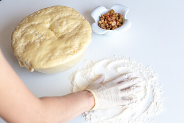 Kneading dough with flour and raisins on a white table close-up