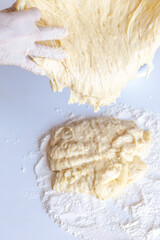 Kneading dough with flour and raisins on a white table close-up