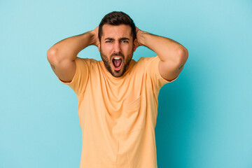 Young caucasian man isolated on blue background screaming with rage.