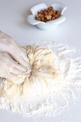 Kneading dough with flour and raisins on a white table close-up