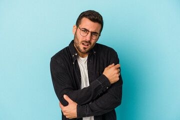 Young caucasian man isolated on blue background massaging elbow, suffering after a bad movement.