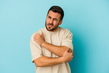 Young caucasian man isolated on blue background massaging elbow, suffering after a bad movement.