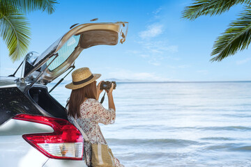 Young woman traveler taking a photo at the beach with car on roadtrip, Summer vacation