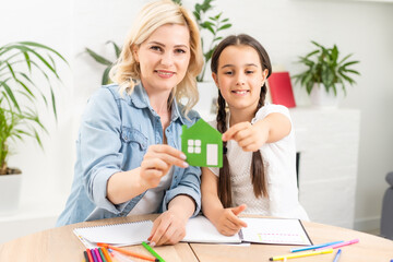 people, charity, family and home concept - close up of woman and girl holding green paper house cutout in cupped hands