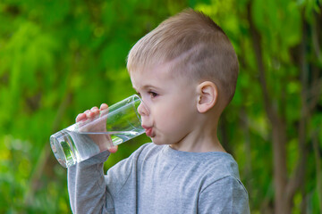 The child drinks clean water in summer. Selective focus.