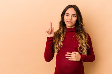 Young mexican pregnant woman isolated on beige background showing number one with finger.