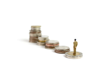Miniature figures businessman stand on coins, on the white backgroud.