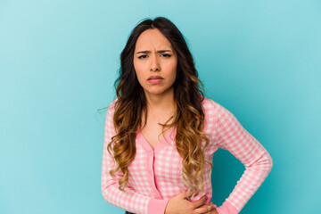 Young mexican woman isolated on blue background having a liver pain, stomach ache.