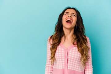 Young mexican woman isolated on blue background shouting very angry, rage concept, frustrated.