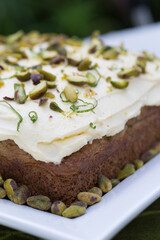 Lime and pistachio cake served on square plate lined with pistachios and beautifully decorated