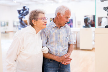 Obraz premium mature European couple examines paintings in an exhibition in hall of art museum