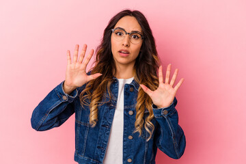 Young mexican woman isolated on pink background rejecting someone showing a gesture of disgust.