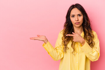 Young mexican woman isolated on pink background excited holding a copy space on palm.