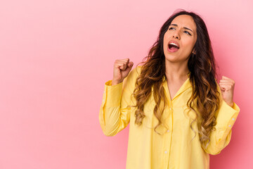 Young mexican woman isolated on pink background raising fist after a victory, winner concept.