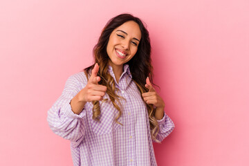 Young mexican woman isolated on pink background pointing to front with fingers.
