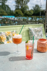 Pink cocktails served outside on a sunny terrace with swimming pool in the background
