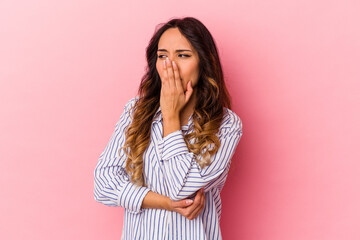 Young mexican woman isolated on pink background yawning showing a tired gesture covering mouth with hand.