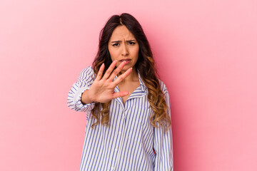 Young mexican woman isolated on pink background rejecting someone showing a gesture of disgust.