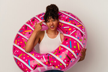 Young mixed race woman holding an inflatable air donut isolated on white background showing a disappointment gesture with forefinger.