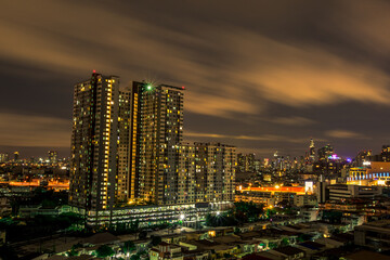 Fototapeta na wymiar The high angle background of the city view with the secret light of the evening, blurring of night lights, showing the distribution of condominiums, dense homes in the capital community
