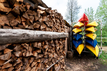 plastic boats for river trips on a rack near chopped firewood