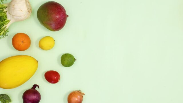 Healthy fresh fruits and vegetables make creative pattern on light green background. Stop motion