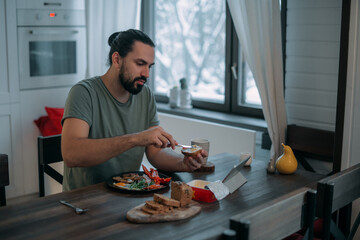 A man is having breakfast at home with a tablet.