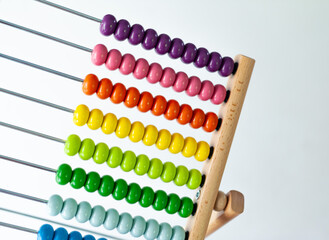 Multi-colored designer background. Calculating Colorful wooden rainbow abacus for number calculation. Close up wooden abacus on white background. Mathematics learning concept. Rainbow colors